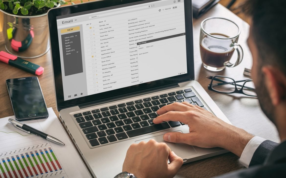 Emails list on a laptop screen, office background